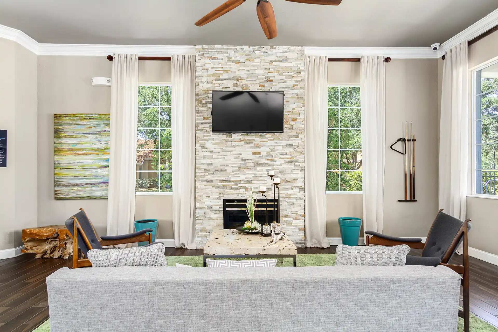 community room with wall art, wall-mounted TV, ceiling fan and windows