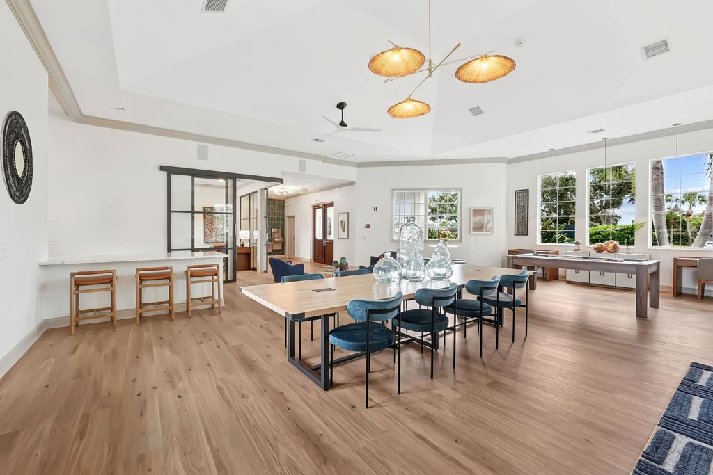 Clubhouse with a long wooden dining table, plush blue chairs, and stylish pendant lighting, perfect for gatherings.